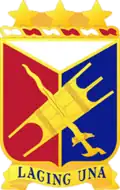 A Gold color metal and enamel device 1+1⁄4 inches (3.2&nbsp;cm) consisting of a shield blazoned: Per pall Argent, Gules and Azure, over the second and third an Igorot war shield and kris in saltire Or. Attached above the shield a wreath of the colors Argent and Gules three mullets Or. Attached below the shield a Gold scroll inscribed 'LAGING UNA' in Blue letters.