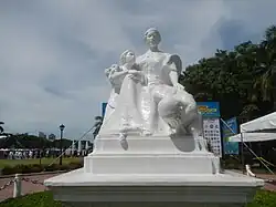 Sculpture of a woman calming a crying man with a young girl resting her arms on the woman's lap