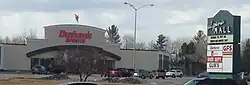 An exterior view of Alpena Mall, with signage visible reading "Alpena Mall" and "Dunham's Sports"