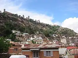 a high stone outcropping with scattered brick houses at the base