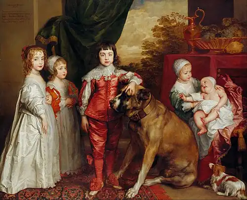 "Portrait of five children dressed in satin clothing of the 16th century, from the left a girl in white, a boy in dress and bonnet, and a regal-looking boy in red breeches in the centre. To the right is a younger girl sitting holding a baby in her arms. A large brown mastiff dog sits in the middle next to the boy and a small white and brown spaniel is in the bottom right."