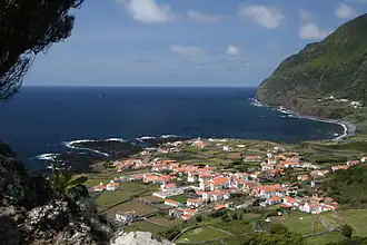 Main village of Fajã Grande, as seen from a local miradouro, showing the coastline to the area of Canto, and the distant escarpment of Ponta da Fajã (far right)