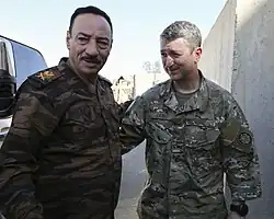 Two men in military uniforms touching backs