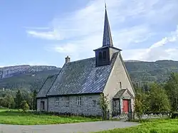 A small grey church with a pointy spire at its front
