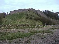 A ruined stone wall on a grassy knoll