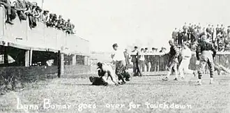 Touchdown photographed from the side, with fans in an end-zone grandstand