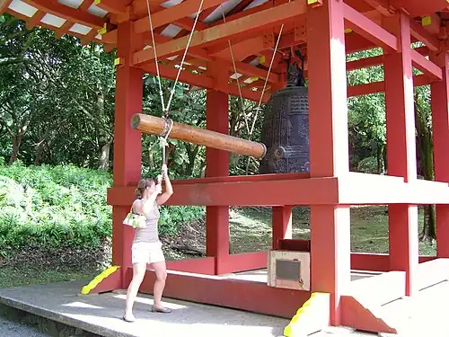 A woman rings the peace bell prior to entering.