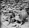A local healer is treating a woman with cupping therapy in front of a loamstone wall.