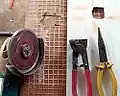 100&nbsp;mm (4") angle grinder with diamond blade, with tiling snips being used to cut holes in tiles