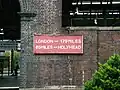 Distance board found in some disrepair on a station wall