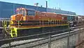 A orange-colored locomotive with two black horizontal stripes