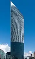 Ground-level view of a thin high-rises's curved, glass facade