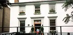 The front-facing side of a house with several people in the doorway