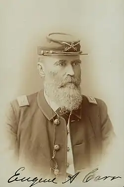 Signed sepia photo shows a bearded man wearing a dark military uniform. He wears a kepi on his head with the number 6.