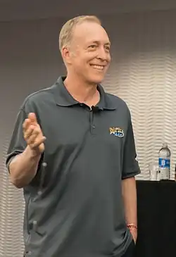 Photograph of a smiling man wearing a grey polo shirt.