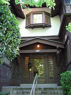 Photograph of the Bowman Apartments, showing a building entry set in a recess of a two-story building with broad, overhanging eaves