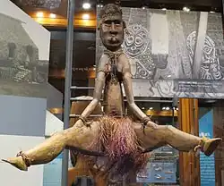 Wooden status of a woman sitting with her legs open