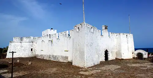Exterior photograph of Fort Metal Cross, Dixcove, Western Region, Ghana. It is composed of two images stitched together taken from just outside