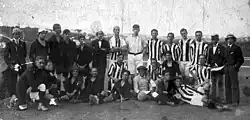 Football players in uniform and other men in suits