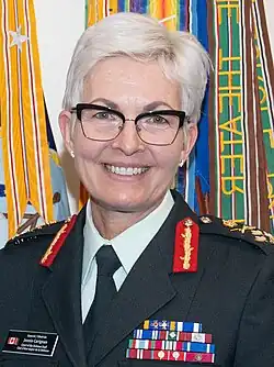 Official portrait, head and shoulder shot with a middle-aged woman with short white hair, wearing a dark uniform and medals.