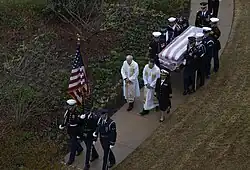 Joint forces honor guard and religious ministers process with the casket to the site of the private family graveside service on December 6, 2018