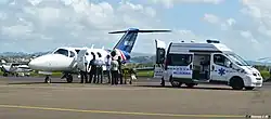 A patient is transferred between an aircraft and an ambulance at Le François airport.