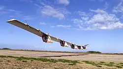 Helios craft photographed from the ground, above a landing area in a desert environment