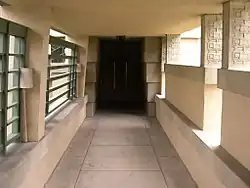 The entrance loggia on the north side of the house. There are metal grilles on the left and half-height partitions on the right.