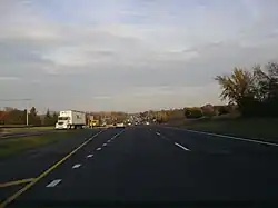 Eastbound IL&nbsp;120 west of Hunt Club Road. Road is divided highway with a grassy median and open areas on both sides with scattered trees.