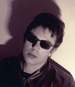 A black and white head and shoulder portrait photograph of a man wearing a leather jacket and sunglasses.