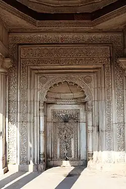 A color photograph of a marble structure inscribed at many places with Persian or Arabic calligraphy