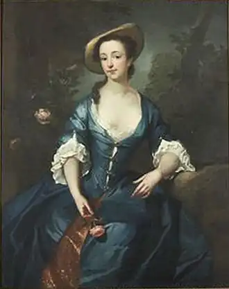 Portrait of a girl, seated, wearing a blue dress and holding a rose.