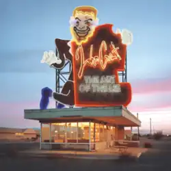 A neon sign of a man with a board reading John Grant and the album title on top of a building.