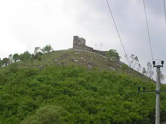 Old castle seen from downhill, with power lines in the foreground