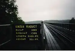 View across the bridge from the bridge deck. A sign indicating the bridge's construction year, reconstruction year, height and length is next to the bridge deck.