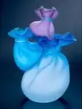 A glass sculpture in three shades of blue resembles a group of satin bags