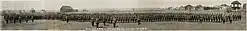 Black-and-white image of military regiment in traditional uniforms, the Lieutenant Coronel on the left in front of his officers, who are lined up horizontally behind him