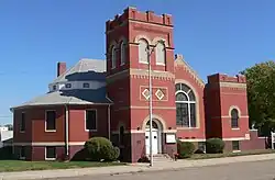 Brick building with square tower; polygonal projection at left