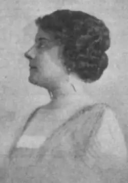 A white woman with dark wavy hair, photographed in profile
