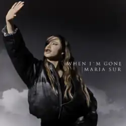Maria Sur standing looking up with her hand extended, which casts a shadow on her face