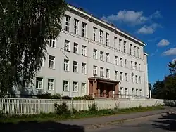 A building with a flat roof and four floors, lined by long rows of tall windows, with two doors in the center of the ground floor