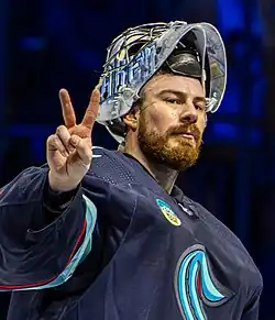 Philipp Grubauer holding up a peace sign while wearing a blue Seattle Kraken hockey jersey