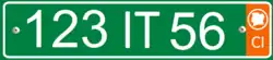Plate with white alphanumeric characters on a green background, and an orange bar on the right side containing the white letters CI at the bottom, and a white silhouette of the Ivory Coast inside a white circle at the top.
