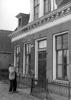 Man waking people by knocking on a bedroom window with a long pole
