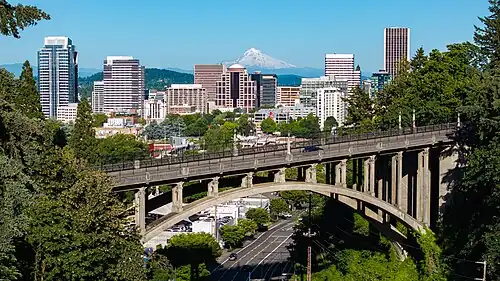 The skyline of Portland, photographed with high-rise buildings behind the Vista Bridge and with Mount Hood in the distance.
