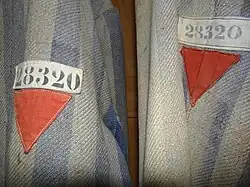 Red emblems of a political enemy on a Dachau detainee's clothing.^