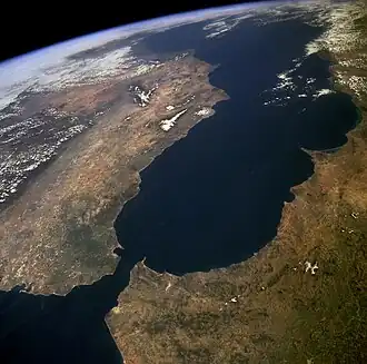 A satellite image of a narrow strip of water separating two land masses