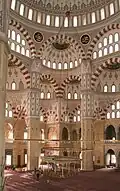 The interior of the mosque showing the symmetry of the mosque, the intricate artwork and calligraphy, and the decorative ablaq in the arches