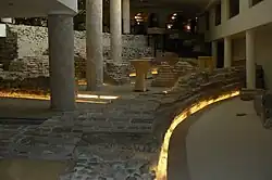 Columns and Roman brick and stone ruins on the ground floor of a hotel lit by yellow lighting