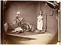 Xie Kitchin as a princess, her brother Brook Taylor Kitchin as Saint George, her brother George Herbert Kitchin as the slain soldier, and her brother Hugh Bridges Kitchin wrapped in the leopard skin rug in St. George and the Dragon on 26 June 1875 by Lewis Carroll.